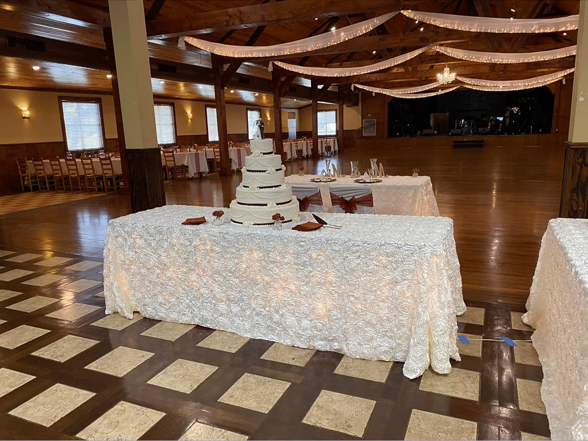 Wedding cake displayed on a table with decorative lighting and floral accents.